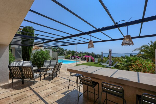 Eine Außenpatio mit Pool, Bar und Liegestühlen.