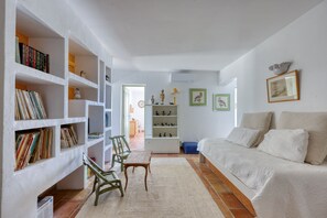 A living room with a white sofa, a bookshelf, a small table, and a chair. - Villa La Chantyviere - Piscine Privée, Pool House (Sainte-Maxime)