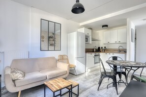 A modern living room with a sofa, a coffee table, and a dining area with a table and chairs. - L'Escale Rouennaise - Proche station de Métro (Rouen)