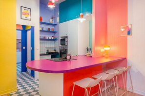 A vibrant kitchen with a central island, bar stools, and modern appliances. - Le Rainbow - Au cœur du centre-ville (Nantes)
