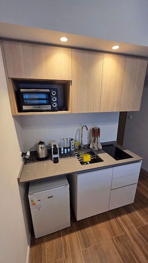 Une cuisine compacte équipée d’un four à micro-ondes encastré, d’une machine à café et d’un petit réfrigérateur.