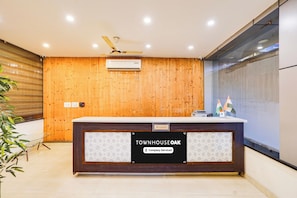 A reception desk with a wooden panel wall, a ceiling fan, and a reception sign.