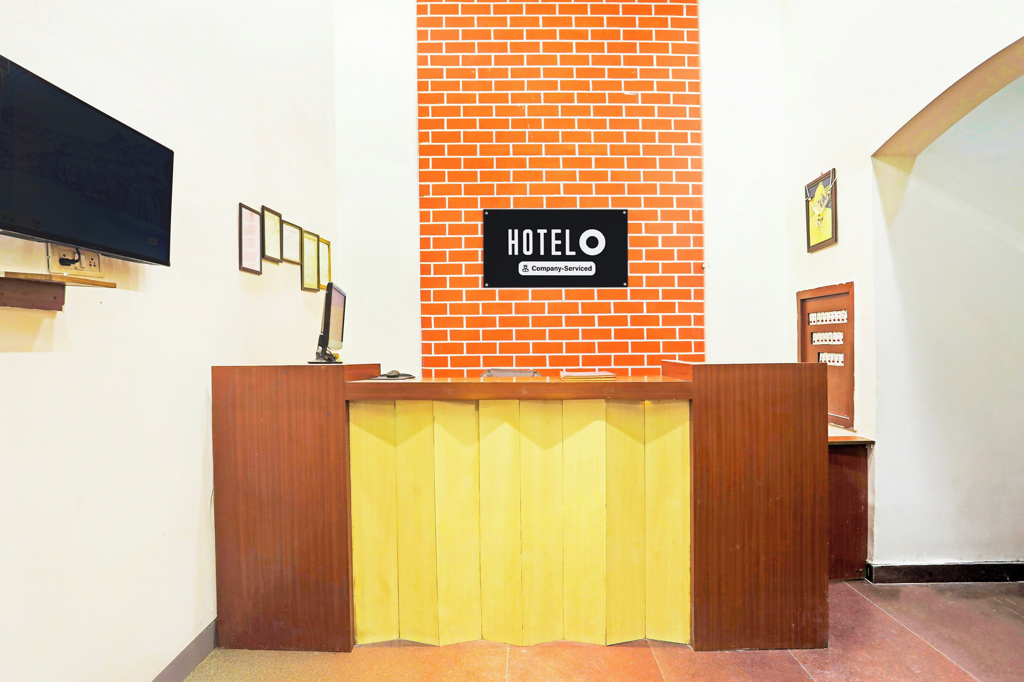 Balcão de recepção de hotel com parede de tijolos ao fundo e placa indicando serviço corporativo.