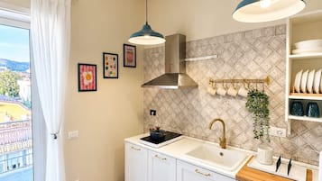 Een moderne keuken met witte kastjes, een roestvrijstalen afzuigkap, een spoelbak en twee hanglampen.