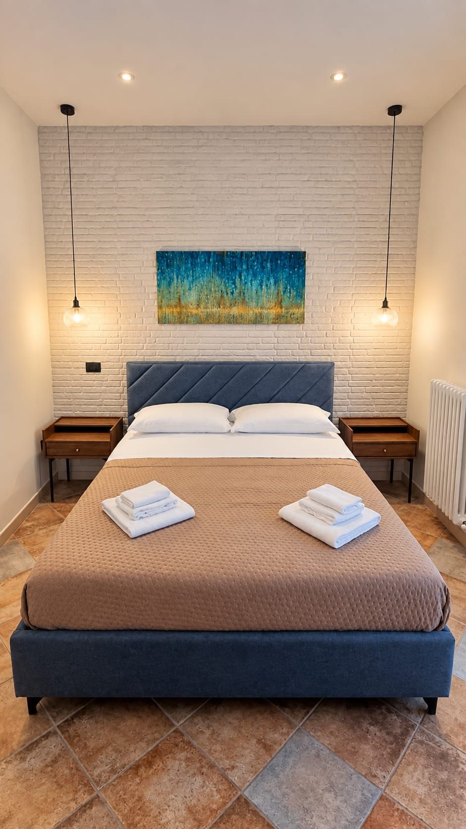 Ein modernes Schlafzimmer mit einem großen Bett, zwei Nachttischen, einem Wandbild und Pendelleuchten.