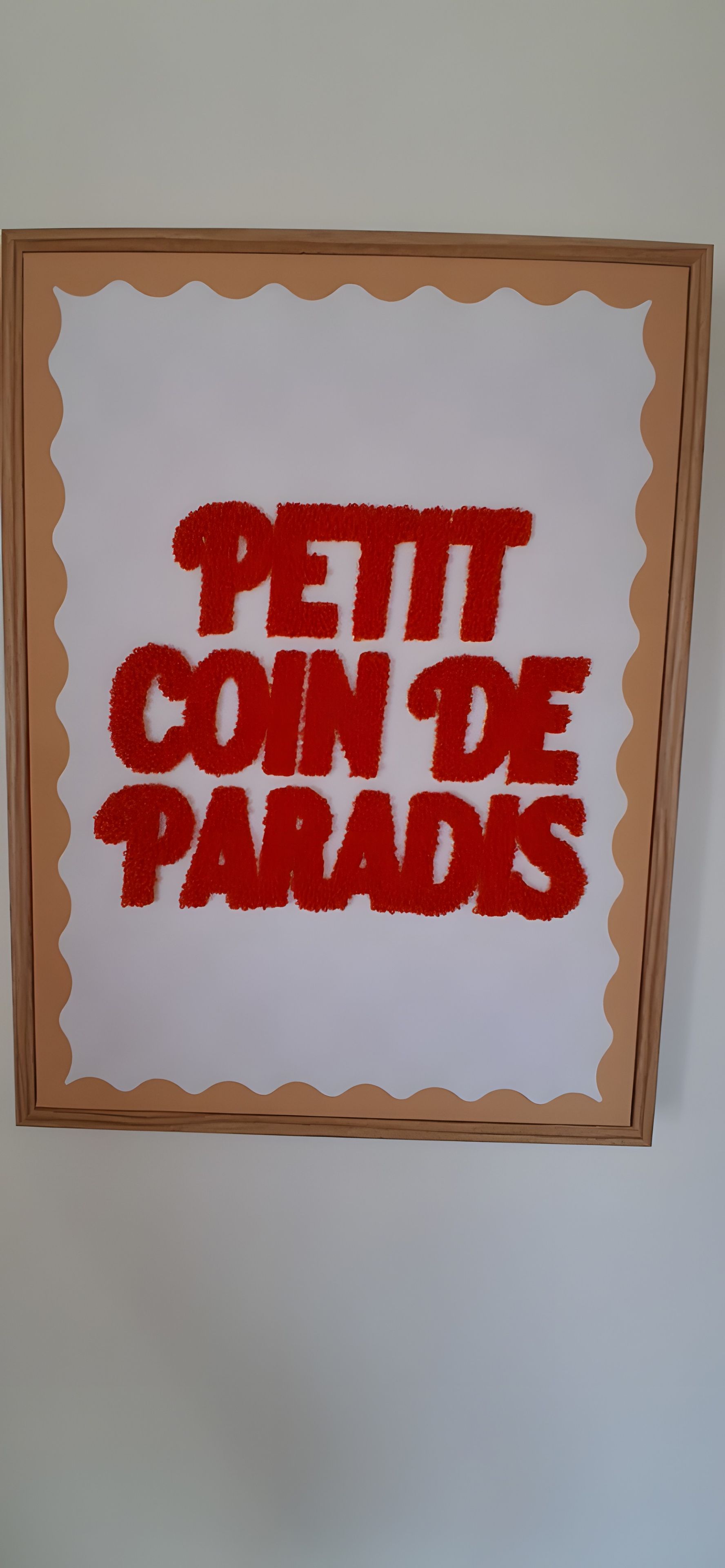 A framed sign with the text 'PETIT COIN DE PARADIS' in bold red letters.