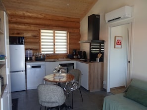 Eine kompakte Küche mit Kühlschrank, Herd und Spüle, ein Esstisch mit Stühlen und eine kleine Wohnbereitschaft mit einer Couch.