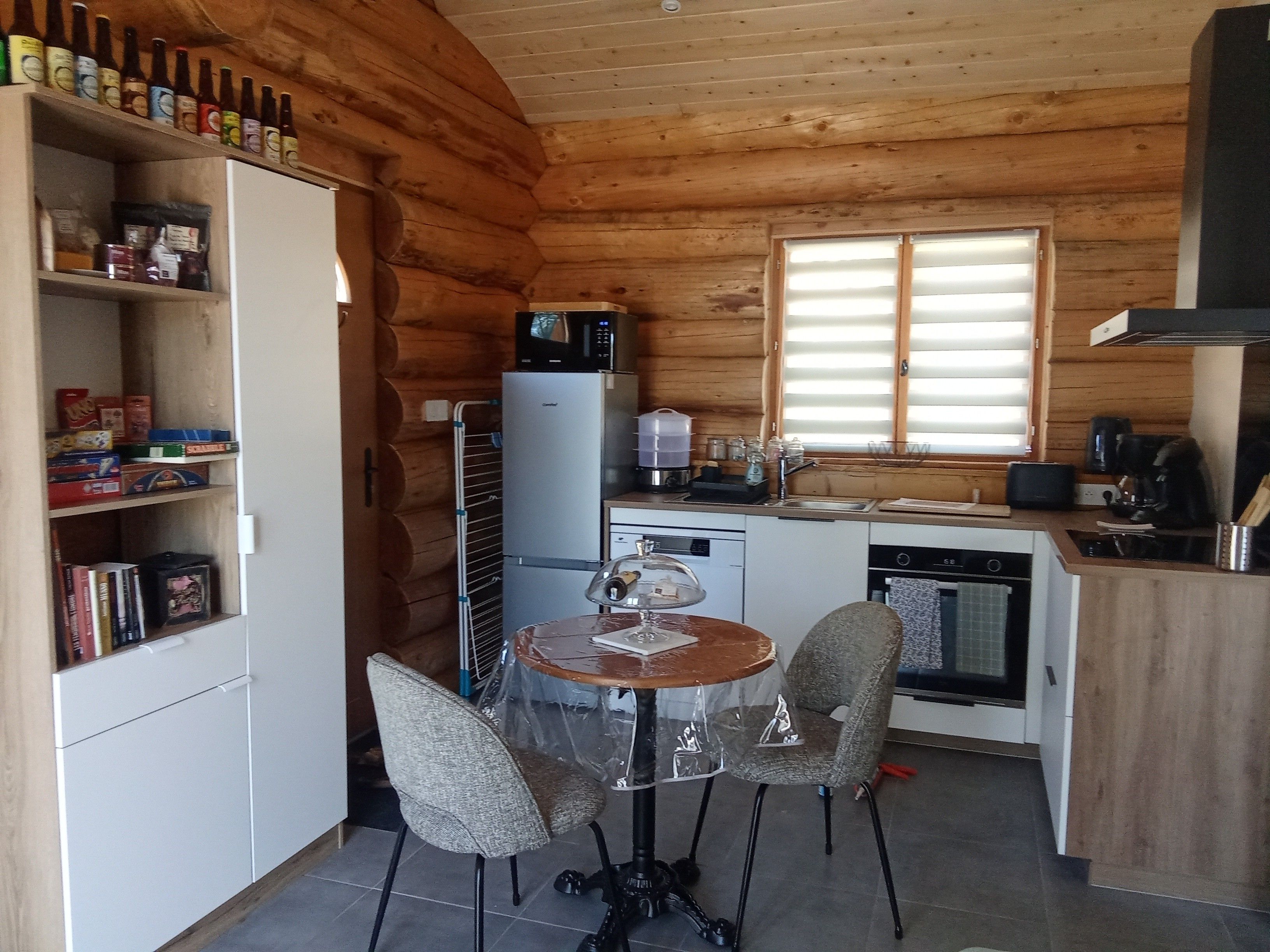 Eine kleine Küche mit Esstisch, Stühlen und einem Kühlschrank.