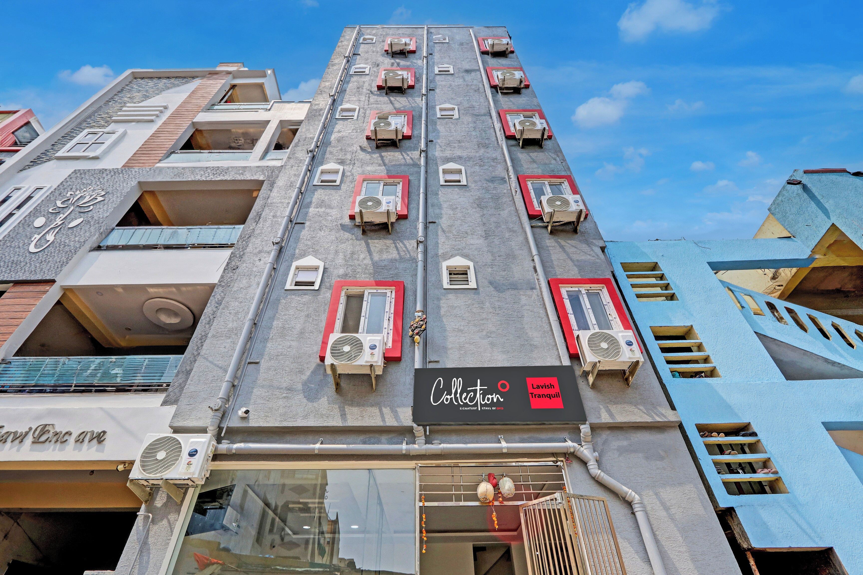 A multi-story building with air conditioning units, a storefront with a sign, and a gated entrance.
