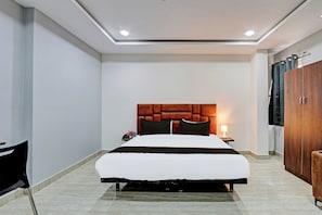 A hotel room with a large bed, a wooden headboard, a nightstand with a lamp, and a wardrobe. - Hotel O Lavish Tranquil (Hyderabad)