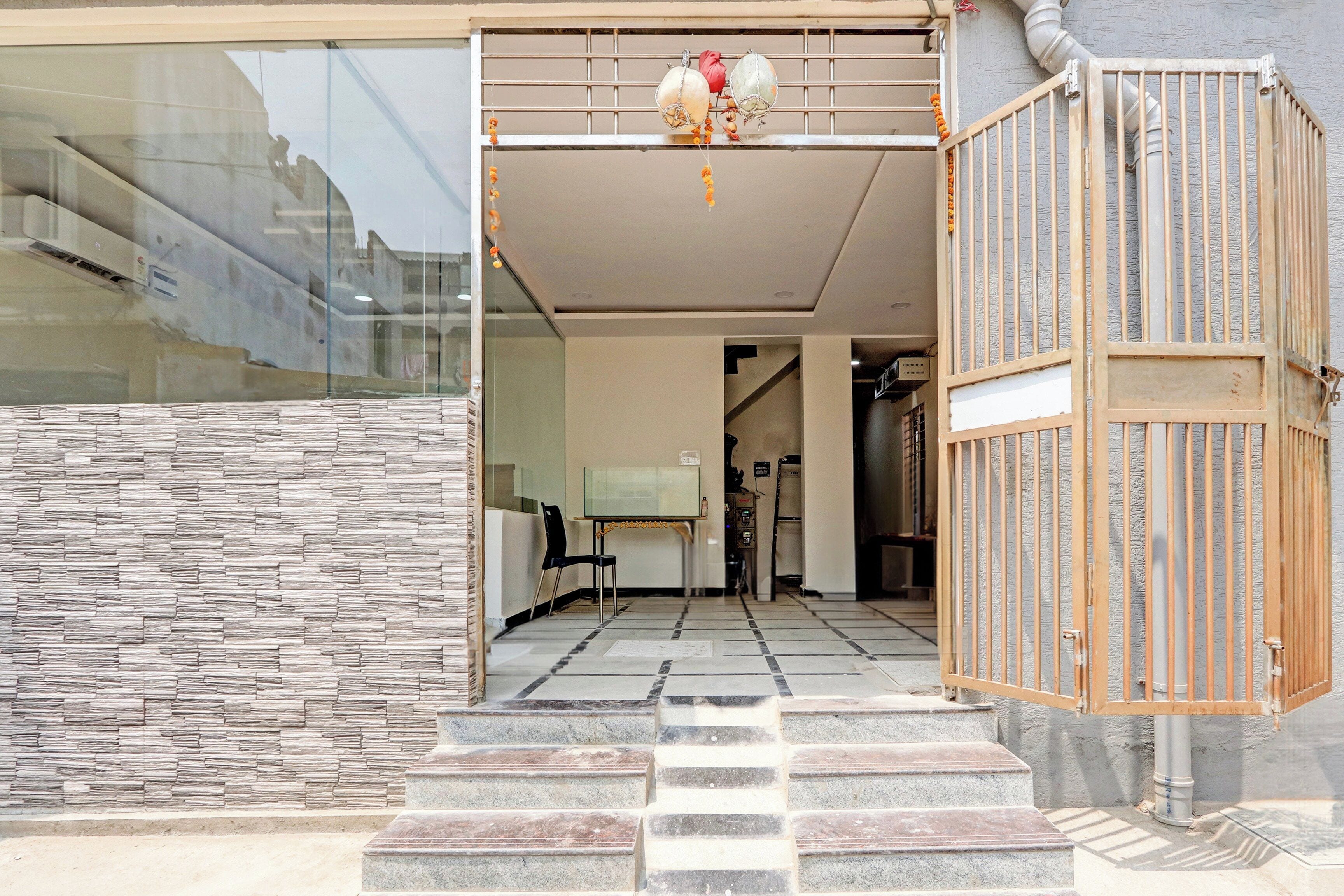 A hotel entrance with a stone facade, a staircase leading inside, and a metal gate.