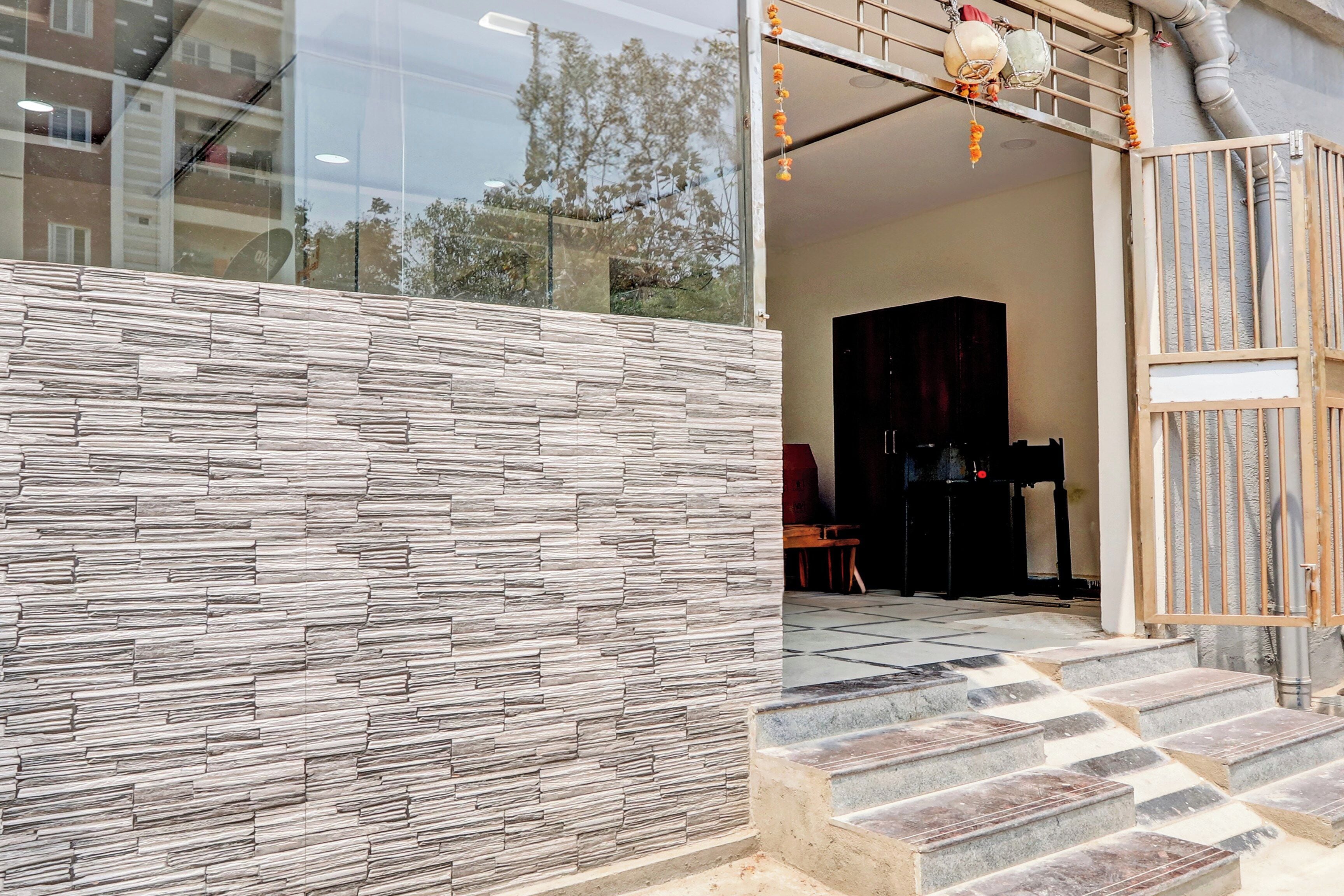 A modern entrance with a stone facade, a staircase leading inside, and a view of the interior through the glass door.