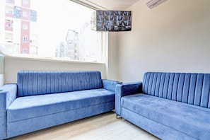 A room with a blue sofa, a window, and a view of buildings outside. - Hotel O Lavish Tranquil (Hyderabad)