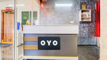 Balcão de recepção com uma placa que diz 'OYO' no saguão de um hotel.