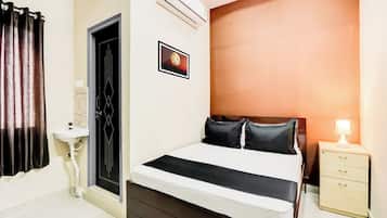 Quarto com cama, mesa de cabeceira, luminária, ar condicionado e quadro na parede.