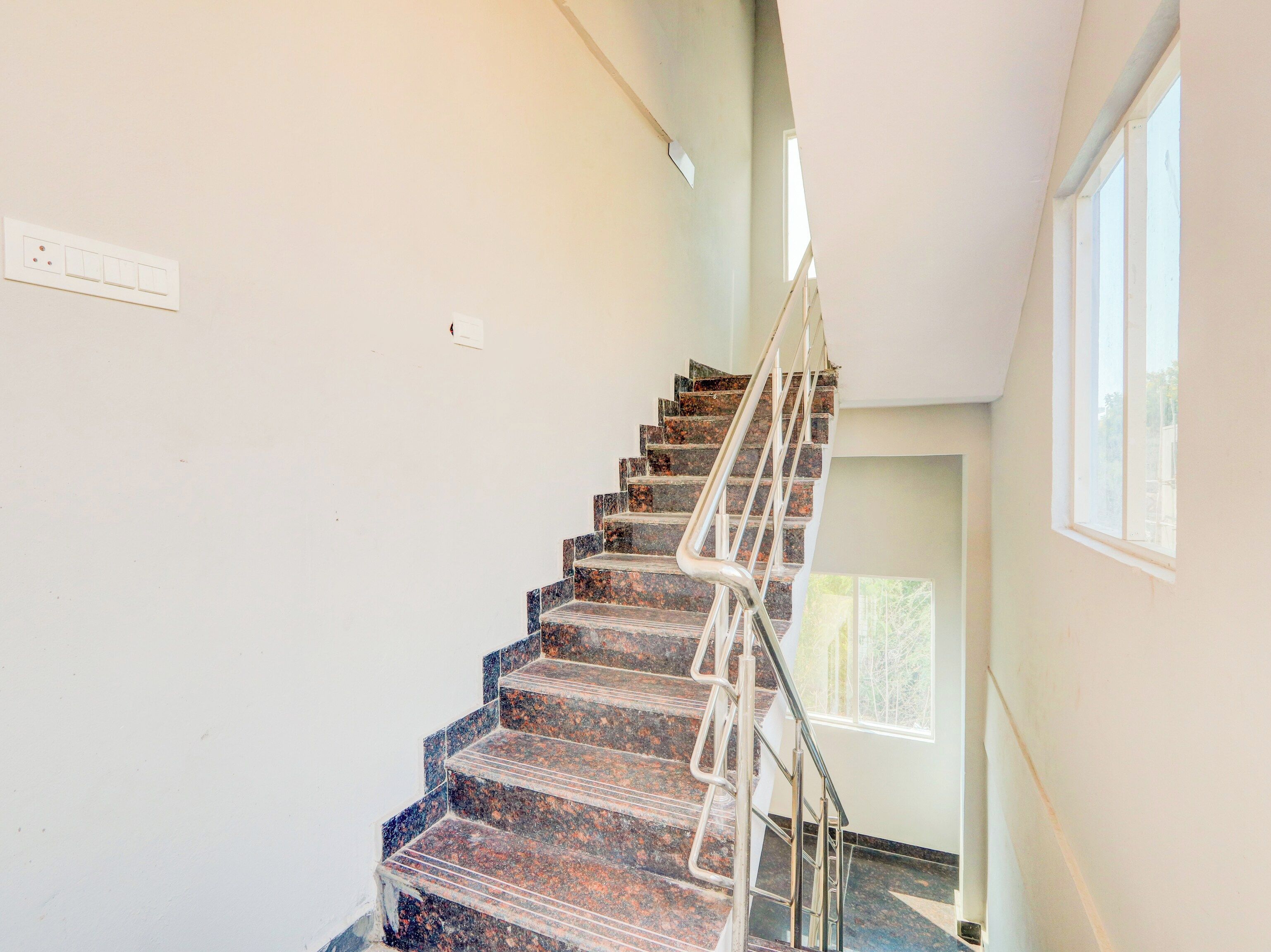 A staircase with a metal handrail, leading to a landing with a window.