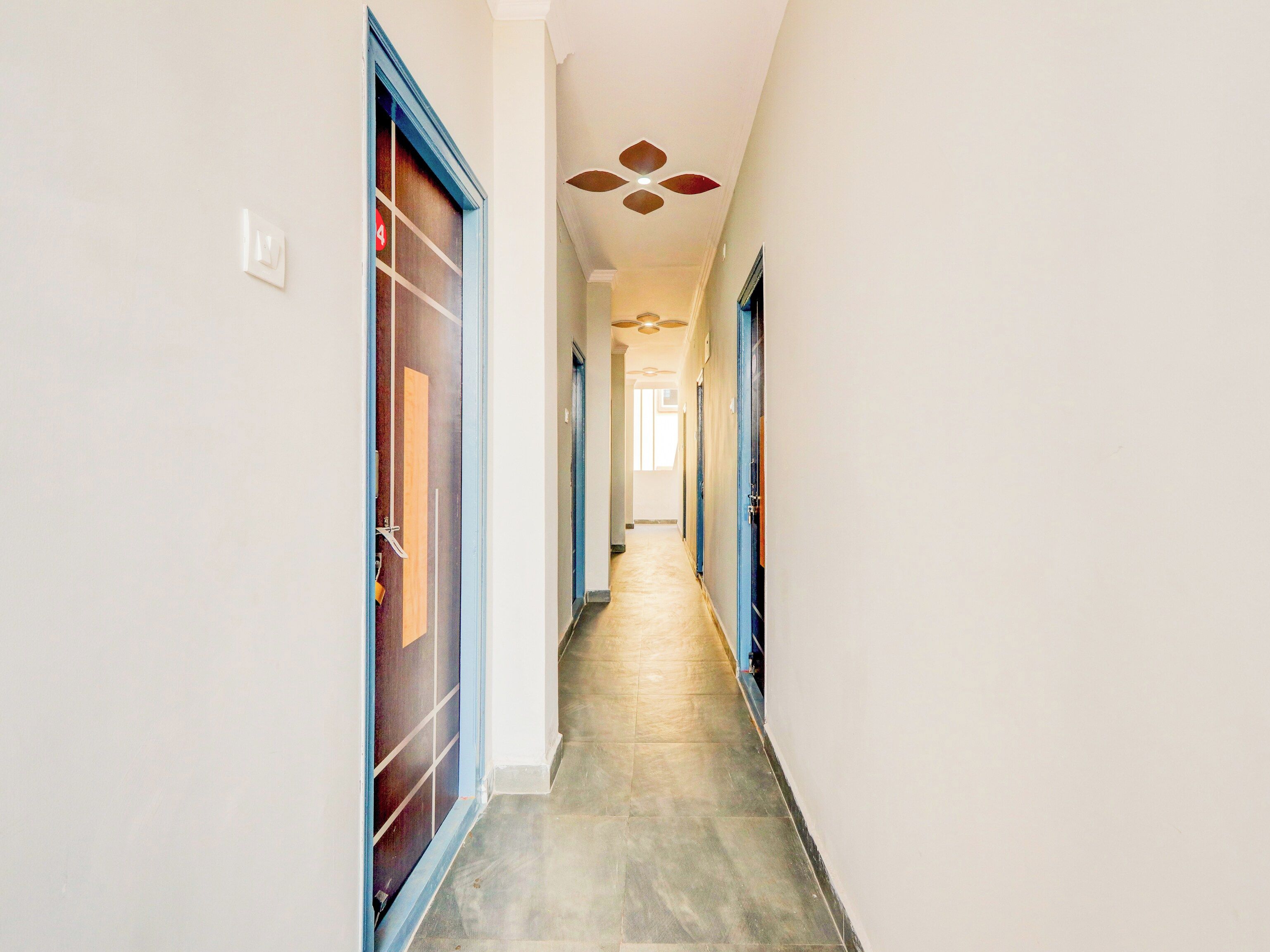 A hallway with doors on both sides, a tiled floor, and a ceiling fan.