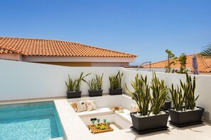 A rooftop terrace with a swimming pool, potted plants, and a seating area with cushions and a fruit tray. - New Listing (Callao Salvaje)