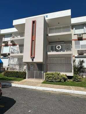 A multi-story building with balconies, a central vertical feature, and a gated entrance. - Beachfront apartment in Luquillo, Puerto Rico!! (Luquillo)