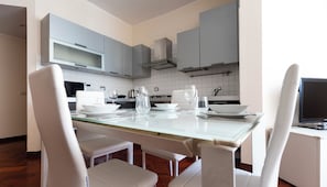 A modern kitchen with white cabinetry, a glass dining table, and white chairs. - Italianway Easy - Sismondi 74 (Milan)