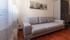 A living room with a grey sofa, a painting on the wall, and a wardrobe. - Italianway Easy - Sismondi 74 (Milan)