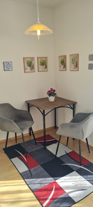 Ein Essbereich mit Tisch, vier Stühlen, einer Hängeleuchte und Wandbildern von Pflanzen.