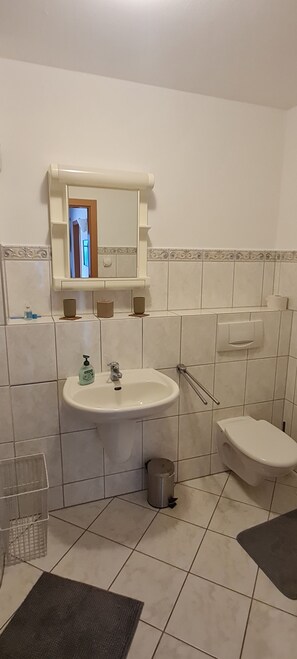 Ein Badezimmer mit Waschbecken, Spiegel, Toilette und Mülleimer.