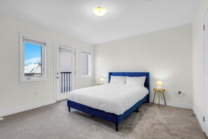 A bedroom with a large bed, two bedside lamps, a ceiling light, and a view of a snowy landscape through a window. - Bright Oakville 3BR Home, Family + Patio & Parking (Oakville)