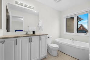 A modern bathroom with a white vanity, a toilet, a sink, and a bathtub. - Bright Oakville 3BR Home, Family + Patio & Parking (Oakville)