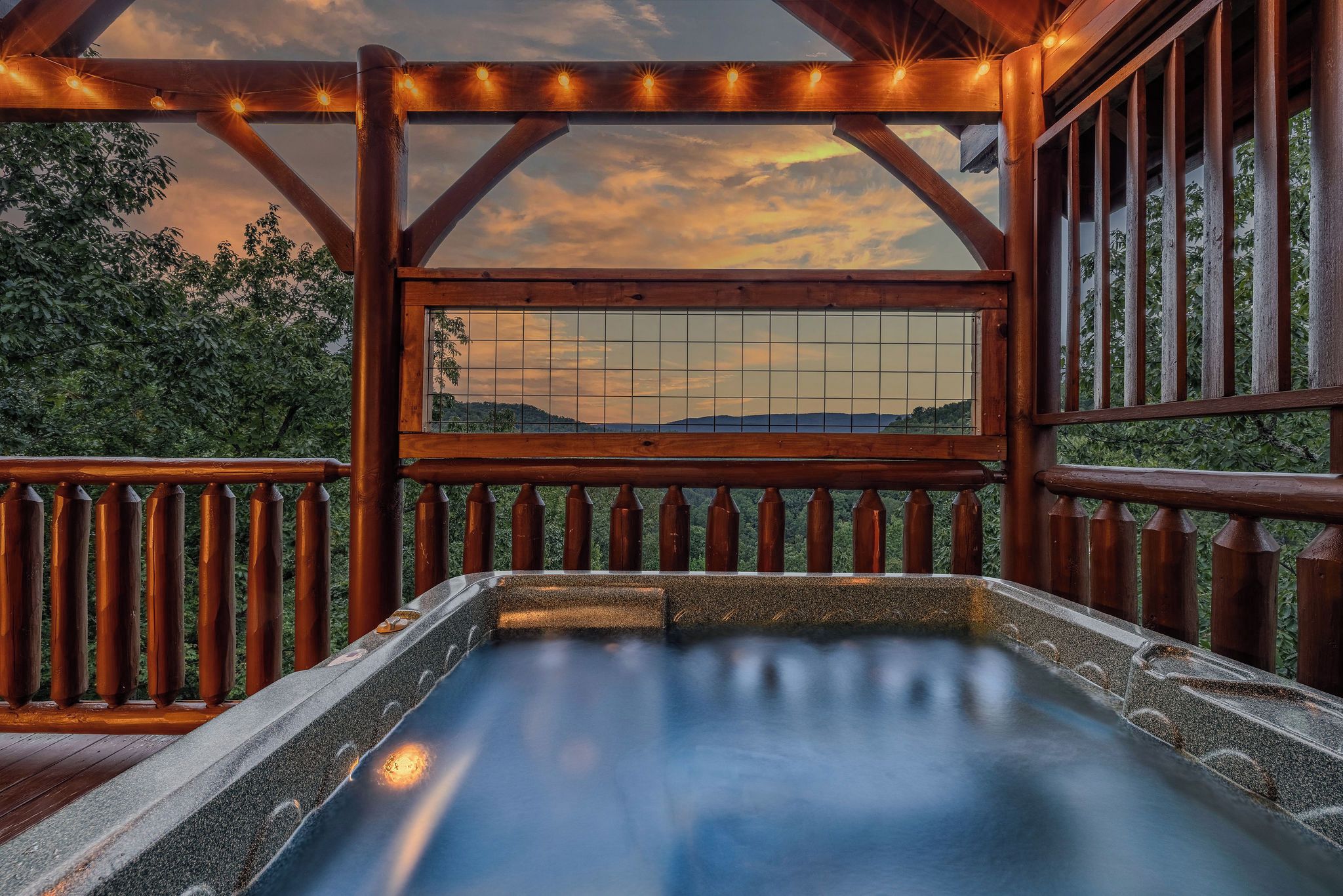 A hot tub with a wooden deck and railing, overlooking a scenic landscape.