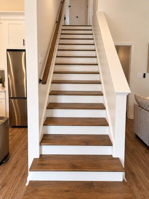 Una escalera con escalones de madera y barandillas blancas, que lleva a una puerta en la parte superior.