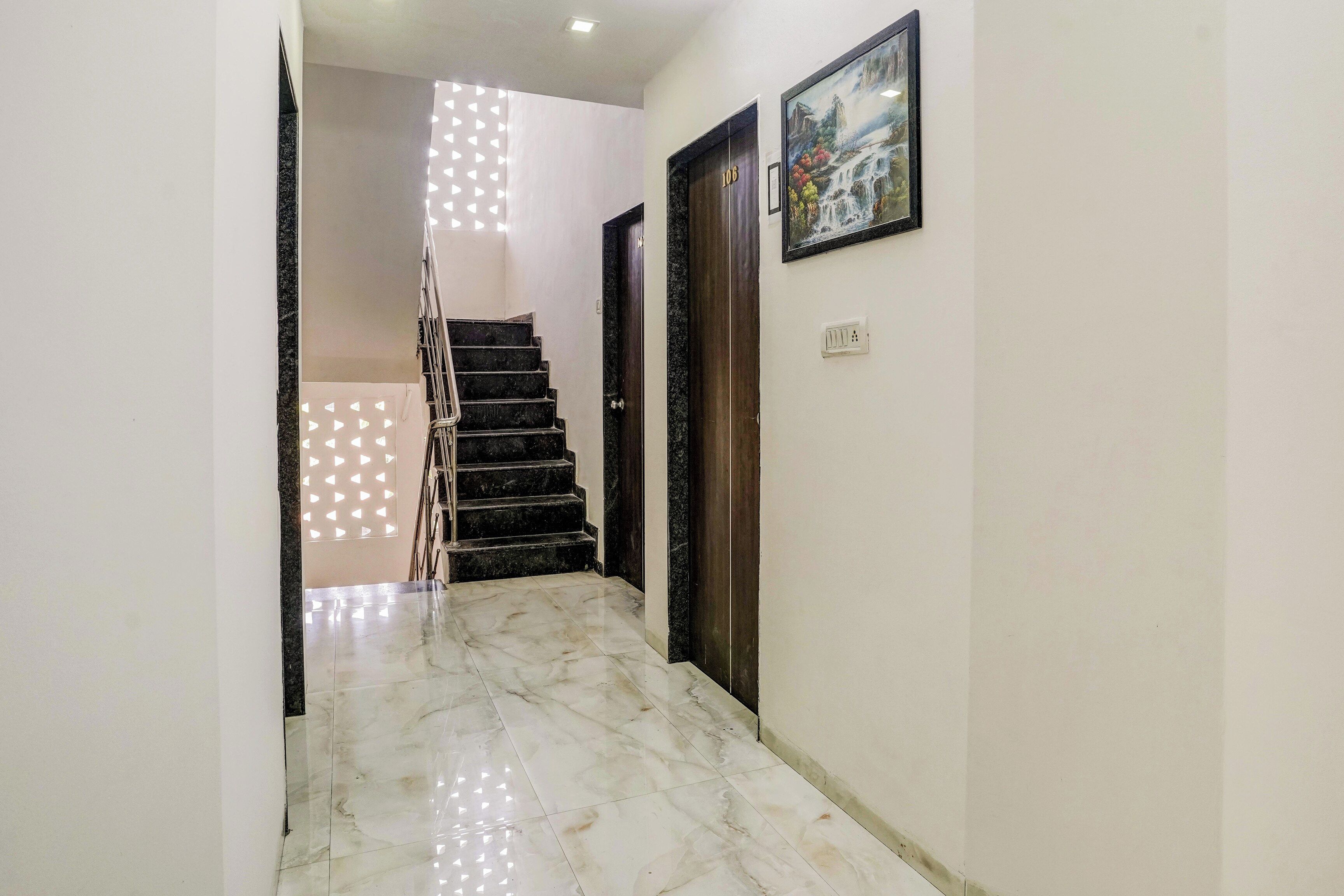 Um corredor com piso de mármore, escada e porta com o número 106.