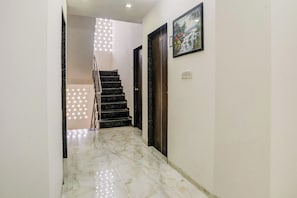 Un pasillo con piso de mármol, una escalera y una puerta con el número 106.