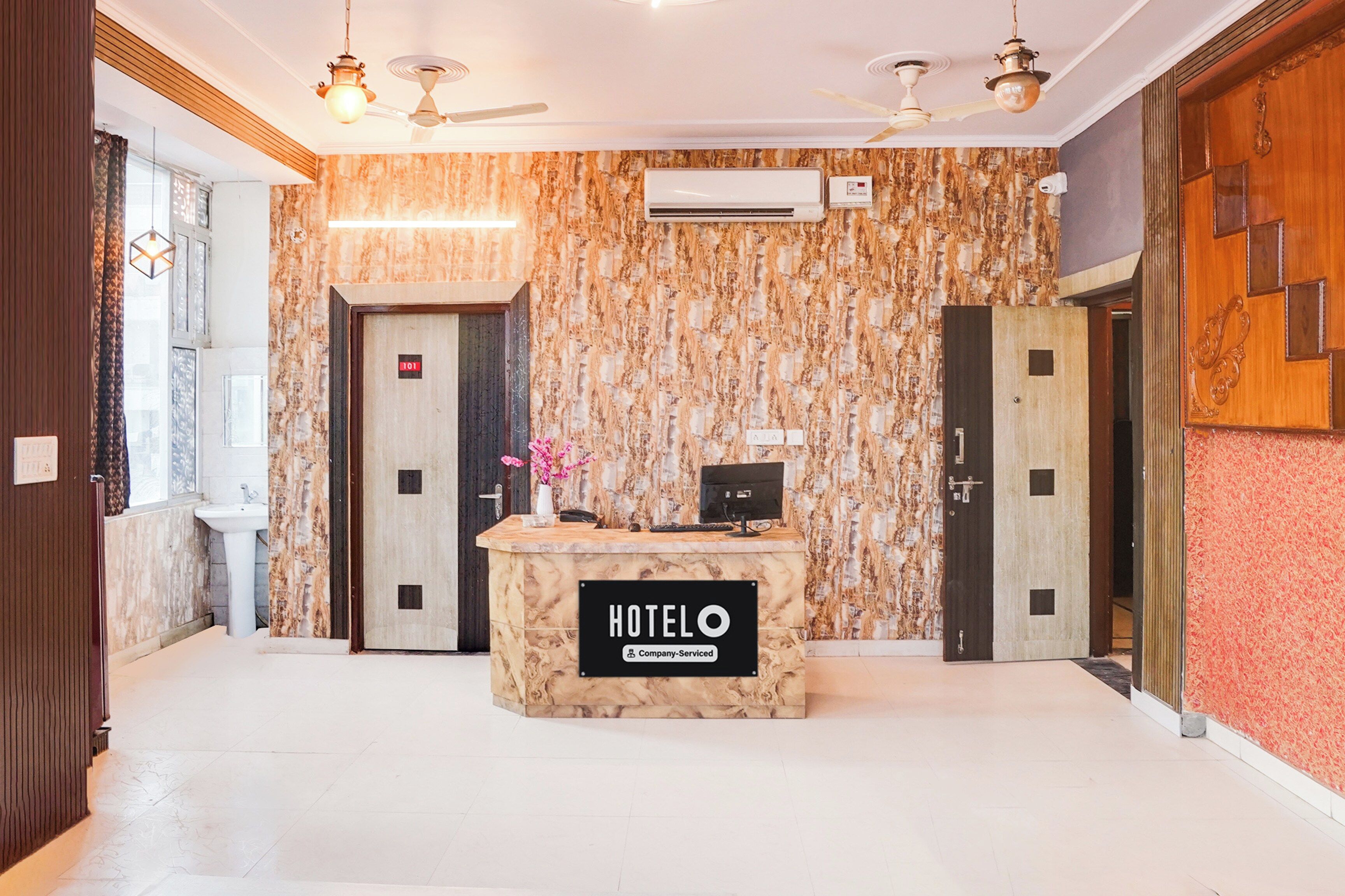A hotel reception area with a marble wall, a reception desk, and two doors.