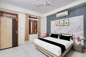 A bedroom with a bed, an air conditioner, a window with curtains, and a wall with framed artwork. - Hotel O Radhaswami Nagar (Jaipur)