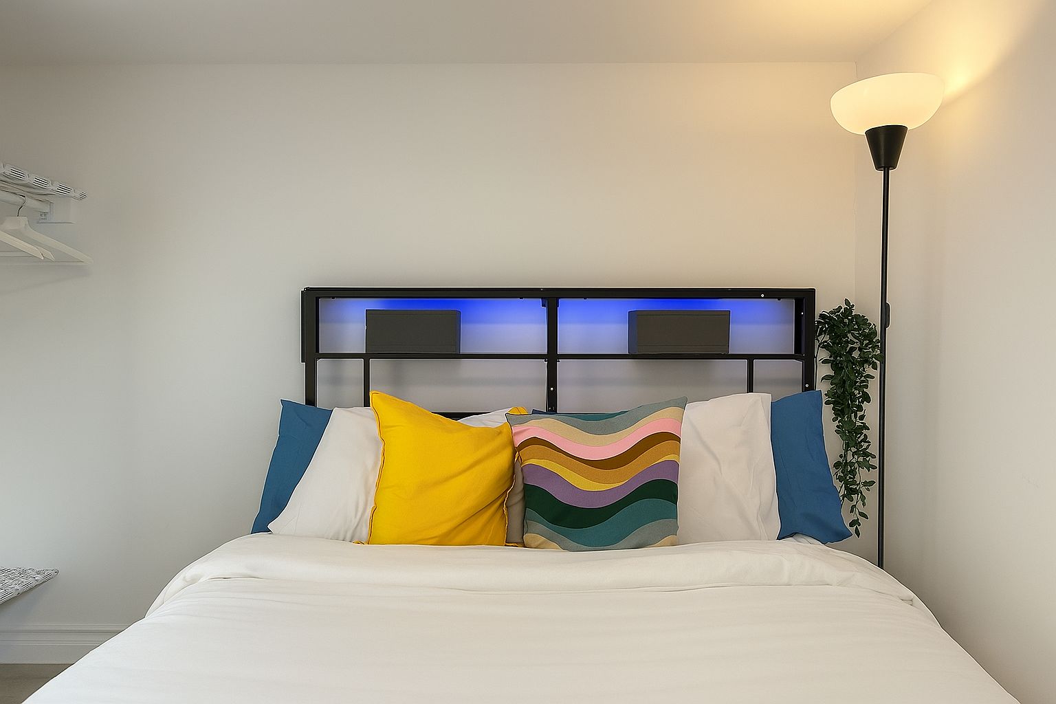 A bed with a white mattress, a black headboard, and colorful pillows.