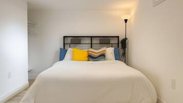 A bedroom with a bed, pillows, a bedside lamp, and a window.