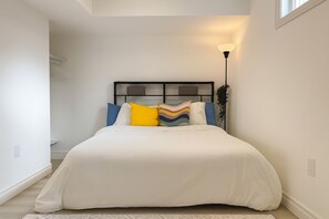 A bedroom with a bed, pillows, a bedside lamp, and a window. - Cozy apartment w/1 Bedroom+ Sofa bed, Parking, near Airport/427/Mall/Market (Toronto)