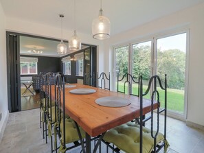 A dining area with a wooden table, metal chairs, and pendant lights. - Panel Place (Hastings)