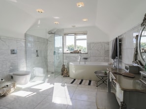 A modern bathroom with a glass-enclosed shower, a freestanding bathtub, and a toilet. - Panel Place (Hastings)