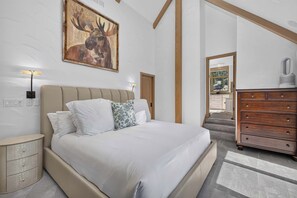 A bedroom with a large bed, bedside tables, a dresser, and a painting on the wall. - Alpine Haus Game Room & Views (Avon)