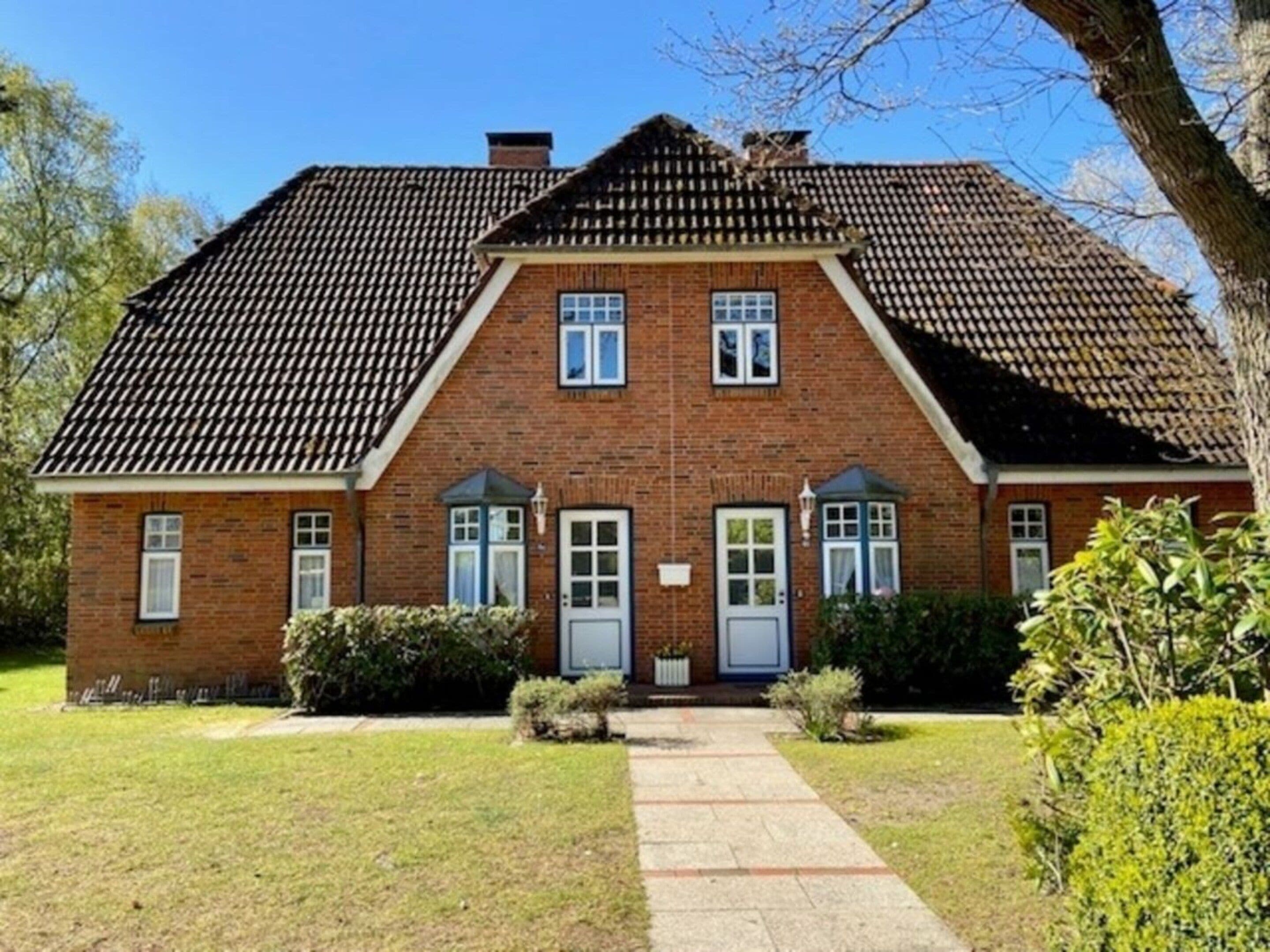 Een herenhuis van baksteen met twee verdiepingen, een symmetrische gevel, een centrale ingang en een klein portaal.
