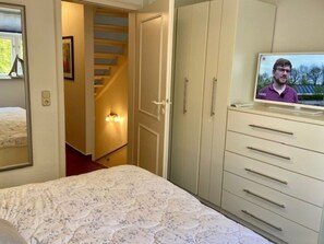 Ein Schlafzimmer mit einem Bett, einem Kleiderschrank, einem Fernseher und einer Treppe.