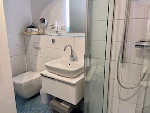Um banheiro com pia branca, vaso sanitário e box de vidro.