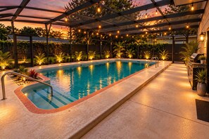An outdoor swimming pool with a pergola overhead, surrounded by potted plants and a barbecue area. - Ultimate Escape | Epic Game Room, Pool, Sleeps 16+ (Longwood)