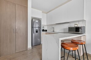 Kitchen with marble counter and wooden bar stools - Distrito Corazón: Bright 2BR w/ Balcony & Pool (Playa del Carmen)