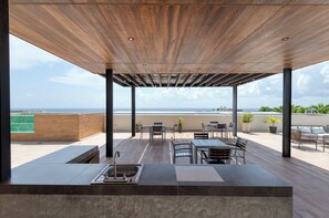 A covered outdoor area with a pool, seating, and a view of the ocean. - Distrito Corazón: Bright 2BR w/ Balcony & Pool (Playa del Carmen)