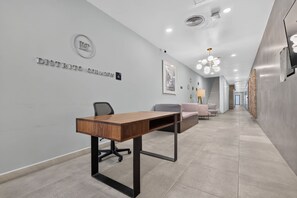 A modern office space with a wooden desk, office chairs, a sofa, and a staircase leading to another area. - Distrito Corazón: Bright 2BR w/ Balcony & Pool (Playa del Carmen)