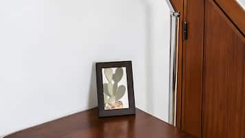 Et træskrivebord med et billedramme, en lampe og et spejl på væggen.