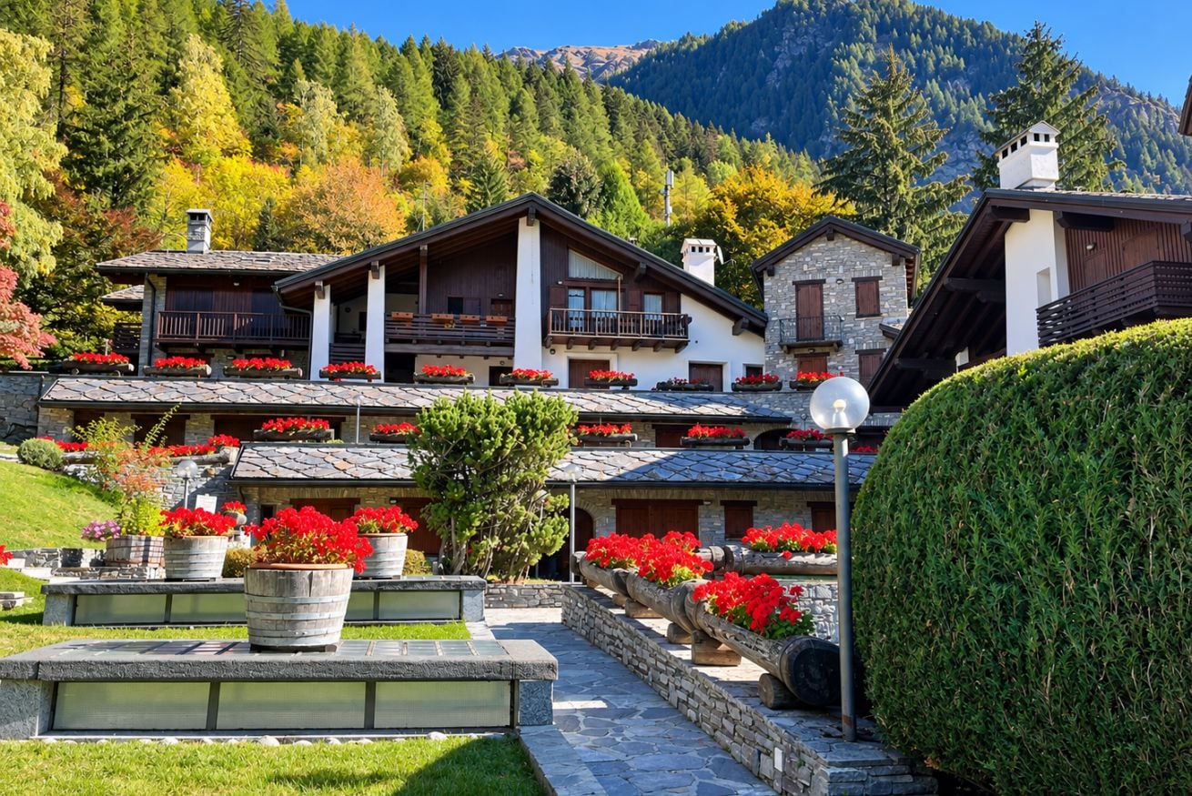 Un bâtiment de style chalet, doté de nombreux balcons, de murs en pierre et de parterres de fleurs rouges.